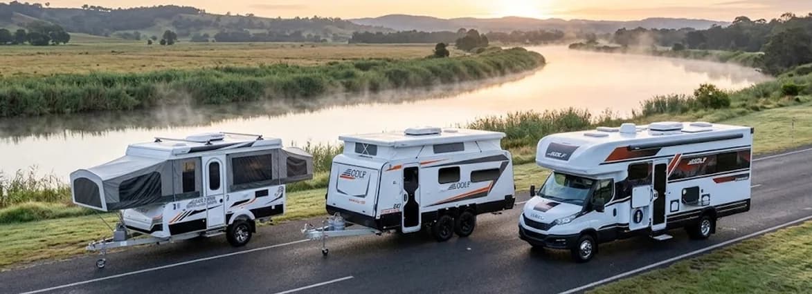Golf caravans travelling beside a river at sunrise